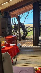 una mesa con un mantel rojo en un porche de madera en Tiny house y casa Parador de playa, en La Pedrera