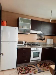 uma cozinha com um frigorífico branco e armários pretos em ESPACIOSO em Tânger