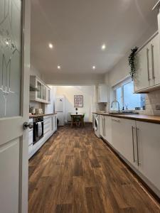 a kitchen with white cabinets and a wooden floor at Town House A in West House Mews in Dunston