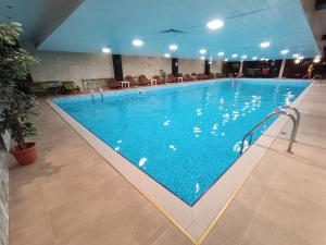 a large swimming pool with blue water in a building at Viva 4 Apartment ski to the door complex Grand Monastery Pamporovo in Pamporovo