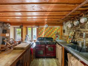 a kitchen with a red stove and a stone wall at La Maison de Max - avec terrasse in Saulxures-sur-Moselotte