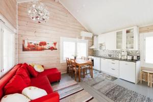 a living room with a red couch and a kitchen at Pikku Torppa Cottage in Kotka