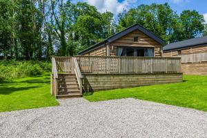 a log cabin with a wooden deck and a porch at Squirrel Lodge 40 with Hot Tub in Newton Stewart