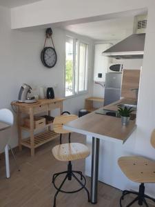 una cocina con mesa y sillas y un reloj en la pared en Studio refait à neuf Ave St Maurice, en Palavas-les-Flots