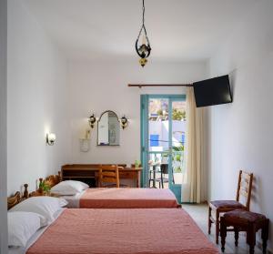 a bedroom with two beds and a desk and a window at Armonia in Kamari +37 photos
