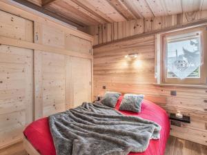 ムジェーヴにあるAppartement Megève, 3 pièces, 4 personnes - FR-1-453-96の木製の部屋に赤いベッドが備わるベッドルーム1室
