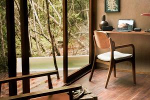 um quarto com uma secretária, uma cadeira e uma janela em OJO DE AGUA. Design+pool. Vive la auténtica selva! em Tulum