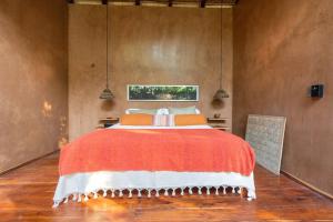 a bedroom with a large bed with an orange blanket at OJO DE AGUA. Design+pool. Vive la auténtica selva! in Tulum