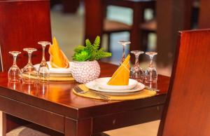 a wooden table with plates and wine glasses on it at Hotel Riviera Ramatou Plage in Lomé