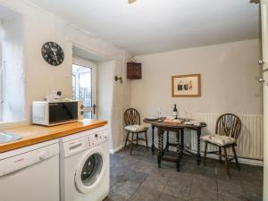 uma cozinha com uma máquina de lavar roupa e uma mesa com cadeiras em Lavender Cottage em Grange Over Sands