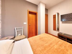 a bedroom with a bed and a chair and a television at Pansion Villa Nur in Mostar