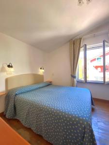 a bedroom with a bed with a blue comforter and a window at Clelia Apartments - Deiva Marina in Deiva Marina