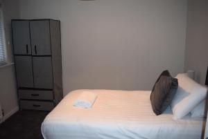 a bedroom with a white bed and a dresser at Kelpies Serviced Apartments- Cromwell Apt in Falkirk