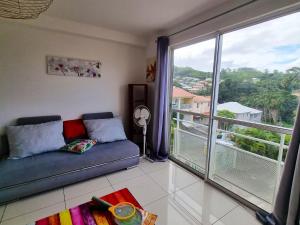 a living room with a couch and a large window at Appartement charmant aux Trois-Îlets 40 m² avec balcon privé in Les Trois-Îlets