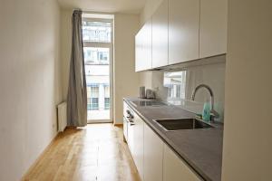 eine Küche mit weißen Schränken, einem Waschbecken und einem Fenster in der Unterkunft Vienna Living Apartments - Ottakring in Wien