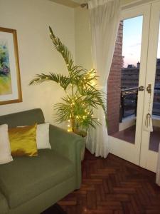een woonkamer met een groene bank en een plant bij Muy agradable departamento. Bien ubicado, luminoso in San Miguel de Tucumán