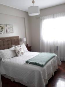 1 dormitorio con 1 cama con sábanas blancas y ventana en Muy agradable departamento. Bien ubicado, luminoso en San Miguel de Tucumán