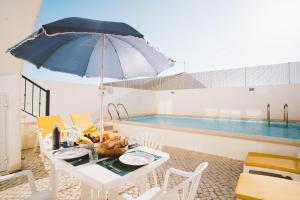 a table with an umbrella next to a swimming pool at Best Houses 31 - Seashell House in Baleal