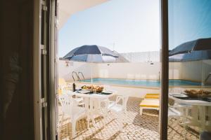 een balkon met een tafel en stoelen en een parasol bij Best Houses 31 - Seashell House in Baleal