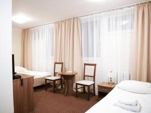 um quarto de hotel com duas camas e uma mesa e cadeiras em Izabella em Puławy