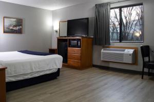 a hotel room with a bed and a flat screen tv at New Victorian Inn & Suites-Norfolk in Norfolk