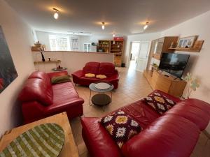 a living room with red leather couches and a tv at Villa Fuchsbau in Hohenfelde