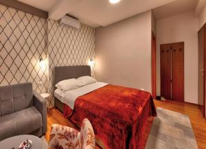 a bedroom with a bed and a couch and a chair at Pansion Villa Nur in Mostar