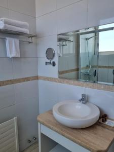 La salle de bains blanche est pourvue d'un lavabo et d'un miroir. dans l'établissement Hotel Plaza Cienfuegos, à Talca