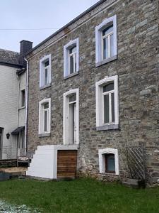 um antigo edifício de tijolos com janelas brancas e uma porta em Maison Maissin em Paliseul