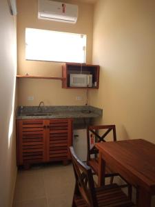 eine Küche mit einer Theke, einem Tisch und einer Mikrowelle in der Unterkunft Kitnetes & Aptos Praia do Capricórnio in Caraguatatuba
