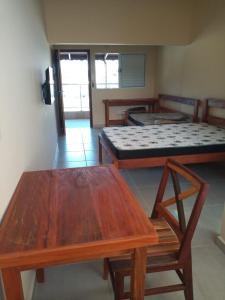 Zimmer mit 2 Betten und einem Tisch in der Unterkunft Kitnetes & Aptos Praia do Capricórnio in Caraguatatuba