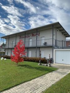 ein Gebäude mit einem roten Baum davor in der Unterkunft Bernstein-Motel Marchegg in Marchegg