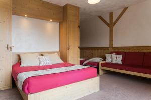 ein Schlafzimmer mit einem großen Bett und einer roten Bank in der Unterkunft Chalet Matsuzaka - chambres d'hôtes de luxe in La Rosière
