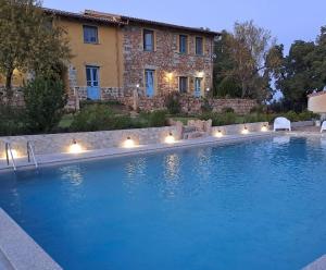 a large swimming pool with lights in front of a house at Agriturismo Is Conchisceddas in Gonnosfanàdiga