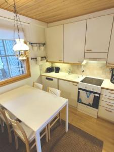 a kitchen with a table and a white table and chairs at Gold Legend Paukkula #4 - Saariselkä Apartments in Saariselka