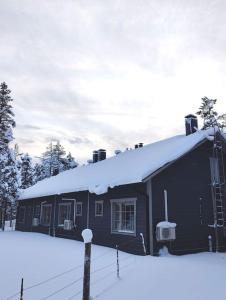 a house with a snow covered roof in the snow at Gold Legend Paukkula #4 - Saariselkä Apartments in Saariselka