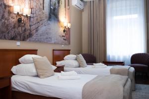 a hotel room with three beds and a painting on the wall at Hotel Wenecki in Częstochowa