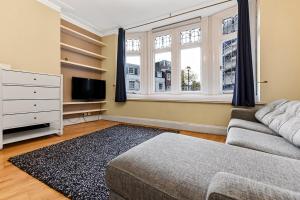 uma sala de estar com um sofá, uma televisão e uma janela em Main Street Corner Great 1bedroom Flat - Richmond em Londres