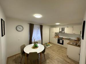 una cocina con mesa y sillas y un reloj en la pared en Apartma Luka, en Ptuj