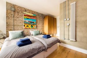 a bedroom with a large bed with blue pillows on it at Cool Loft in fashionable East London in London