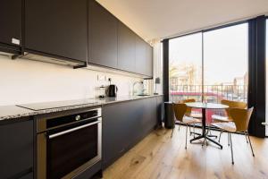a kitchen with black cabinets and a table with chairs at Cool Loft in fashionable East London in London