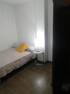 1 dormitorio con cama y mesa con almohada amarilla en Apartamento Reina en Alcantarilla