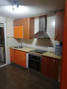 a kitchen with wooden cabinets and a stove top oven at Apartamento Reina in Alcantarilla