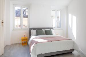 a white bedroom with a large bed with two windows at Stylish apartment - Casa Leone - Center in Trieste