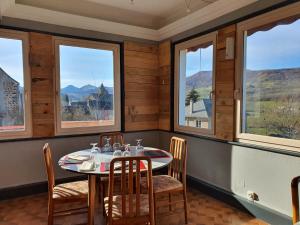 a dining room with a table and chairs and windows at Grand Hotel de la Vallée in Cheylade