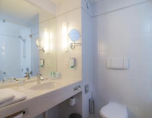 a bathroom with a sink and a toilet and a mirror at Hotel Metropol in Sankt Pölten