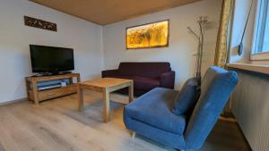 a living room with a blue chair and a television at Gästehaus Wolf in Elbigenalp