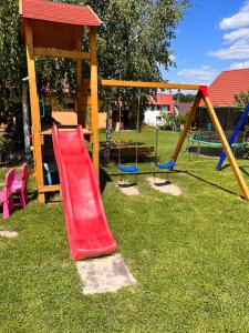 um parque infantil com um escorrega vermelho na relva em Domki całoroczne U Iwony em Kudowa-Zdrój