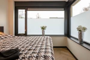 een slaapkamer met een bed en 2 ramen bij Luxe Studio Liemers in Lelystad