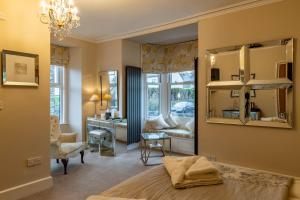 1 dormitorio con cama, escritorio y espejo en Holly Lodge Guest House with FREE off site health club, en Windermere